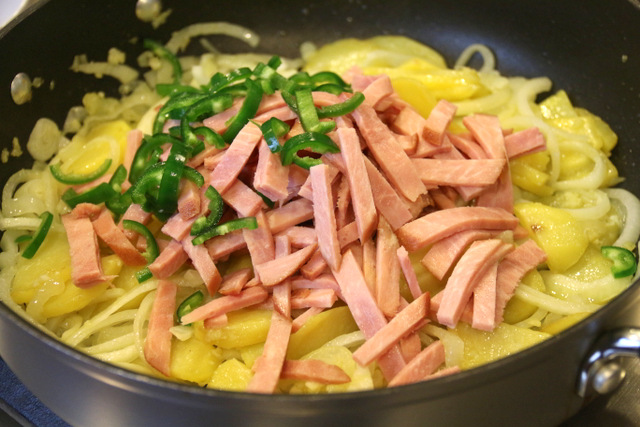 加入火腿和辣椒，再煮5分钟或直到土豆嫩